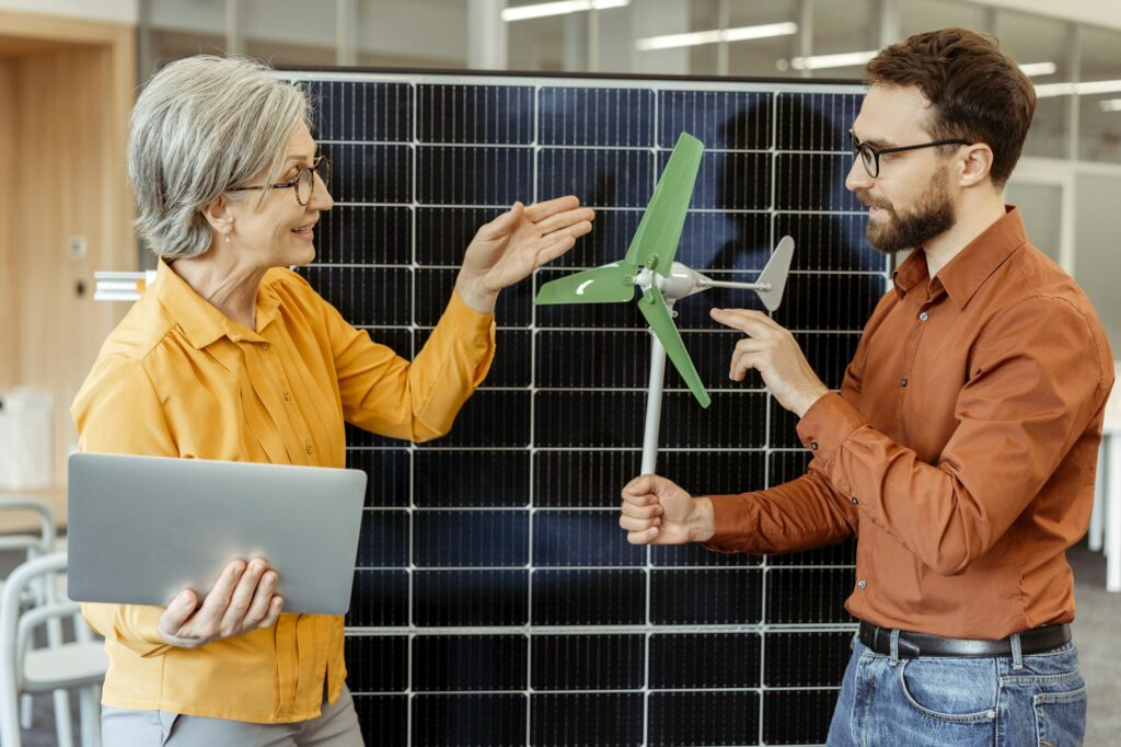 Smiling engineers, developers talking, planning project, cooperation using solar panel and windmill